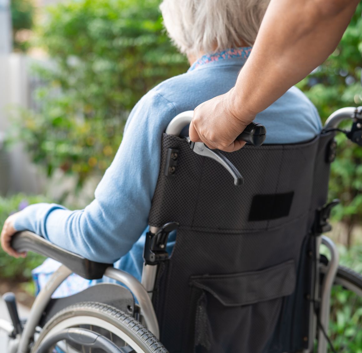 A caregiver pushing an older adult in a wheelchair represents our End-of-Life Care in Clearwater