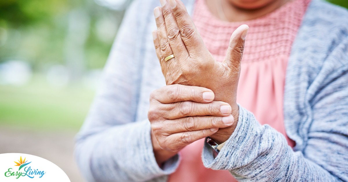 A senior woman holds her hand in pain, representing arthritis and what Arthritis Awareness Month can help with.